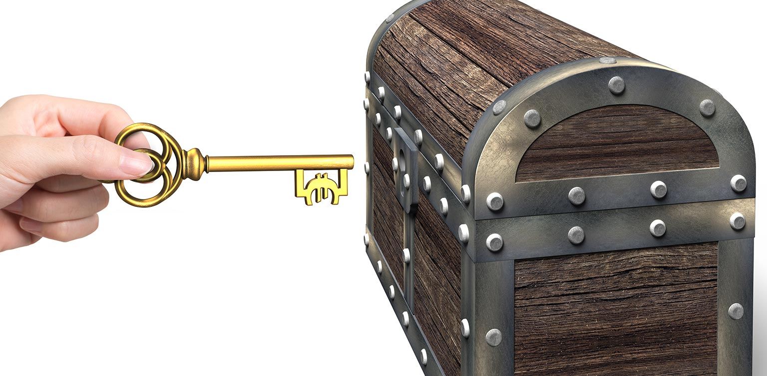a hand holding an old-fashioned key about to open a treasure box