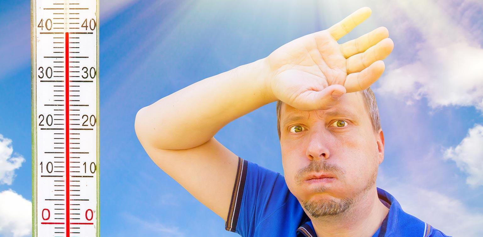 A man blowing out his cheeks and shading his face with his hand with an extra-large thermometer to one side