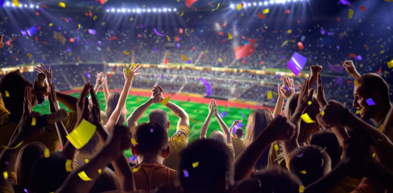 A panoramic photo of a soccer stadium filled with a cheering crowd