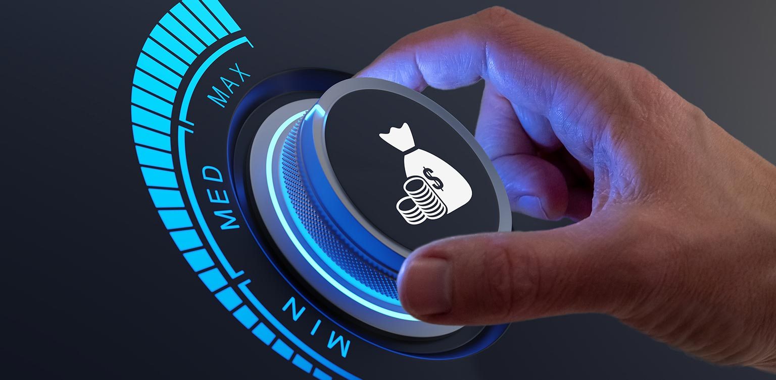 A photo of hand turning a dial featuring coins and a money bag to Max